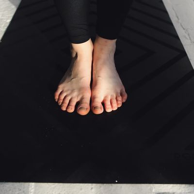 Close-up of feet on a yoga mat, indicating grounding and stability.